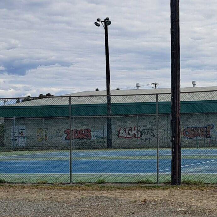 Terrain de tennis clôturé lors d'une journée de printemps nuageuse.